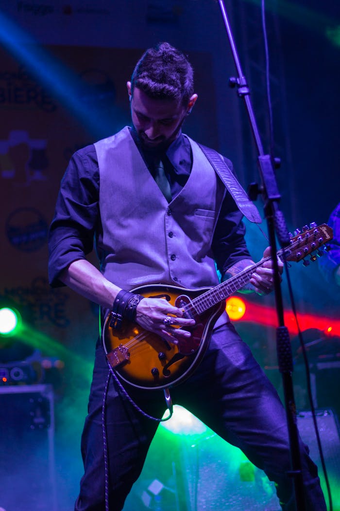 Male musician passionately playing mandolin on stage during a vibrant live concert.